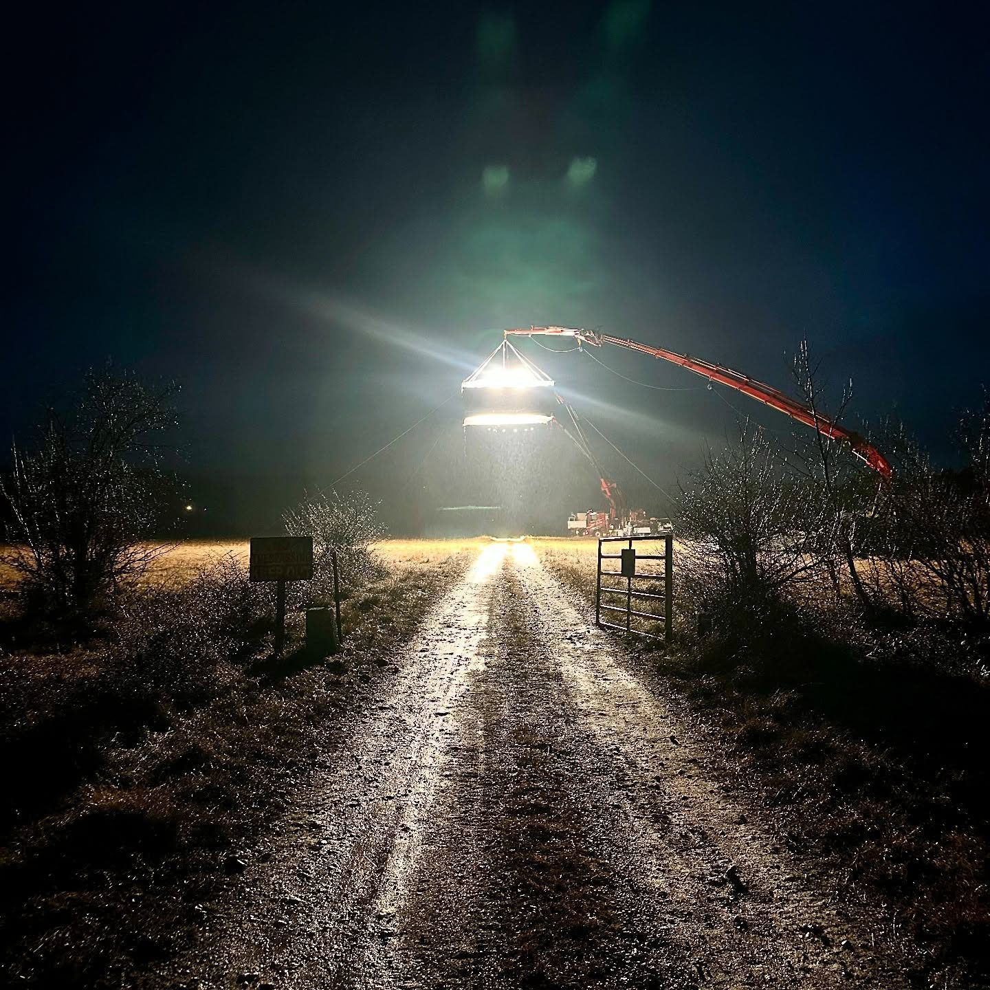 Crane light beaming down a dirt track at night