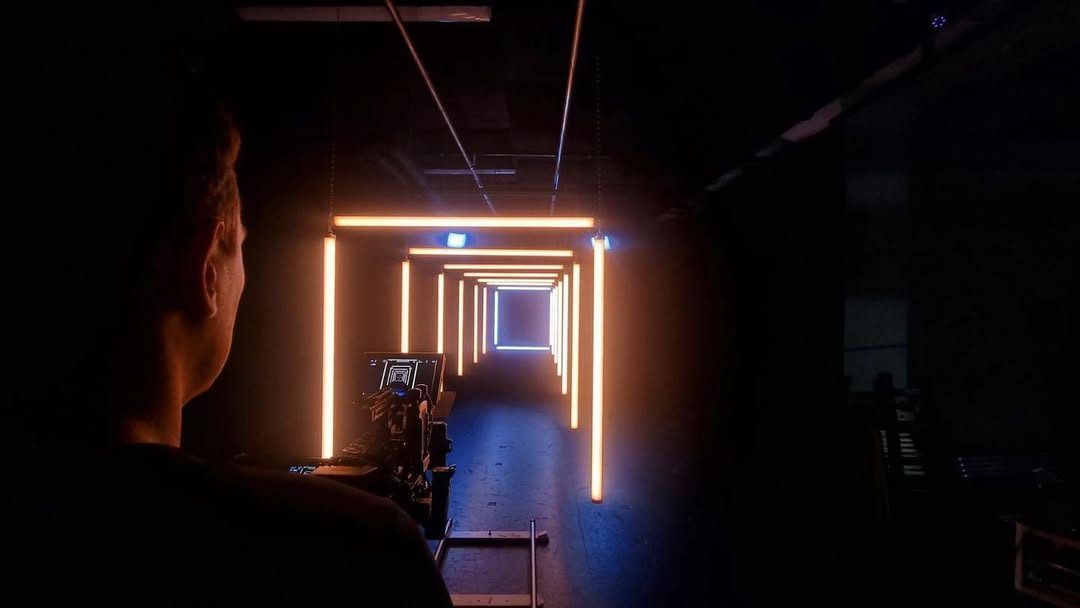 Silhouette facing a corridor of glowing orange LED frames
