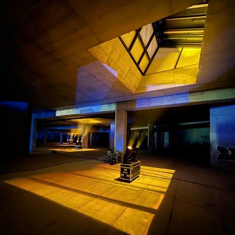 Brutalist concrete interior cut by shafts of yellow light