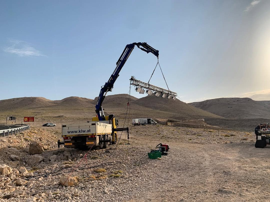 Truck crane raising a lighting array at blue hour in the desert