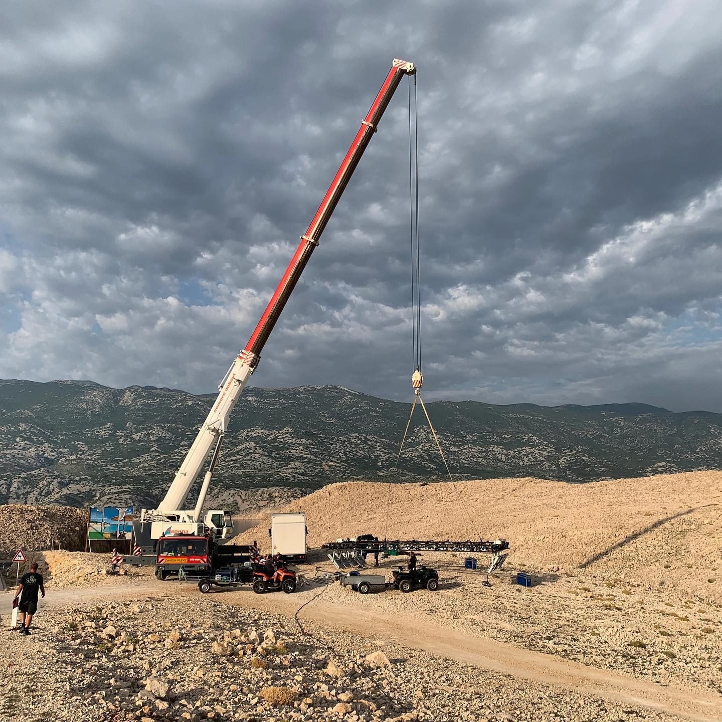 Large red mobile crane on a desert location under a stormy sky