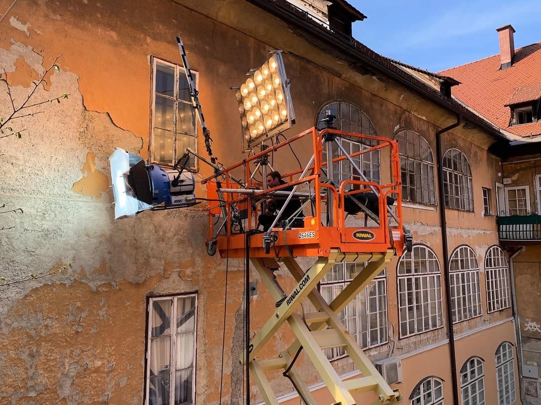 Scissor lift pushing a light through a window of a weathered facade