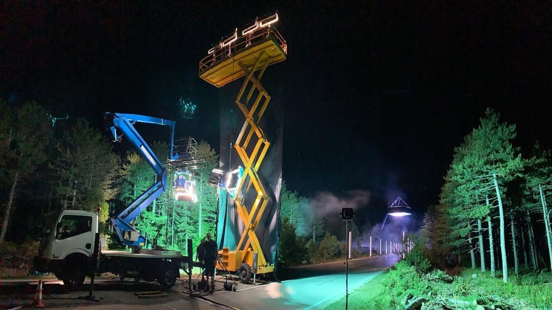 Scissor lifts and cherry pickers lighting a forest road at night
