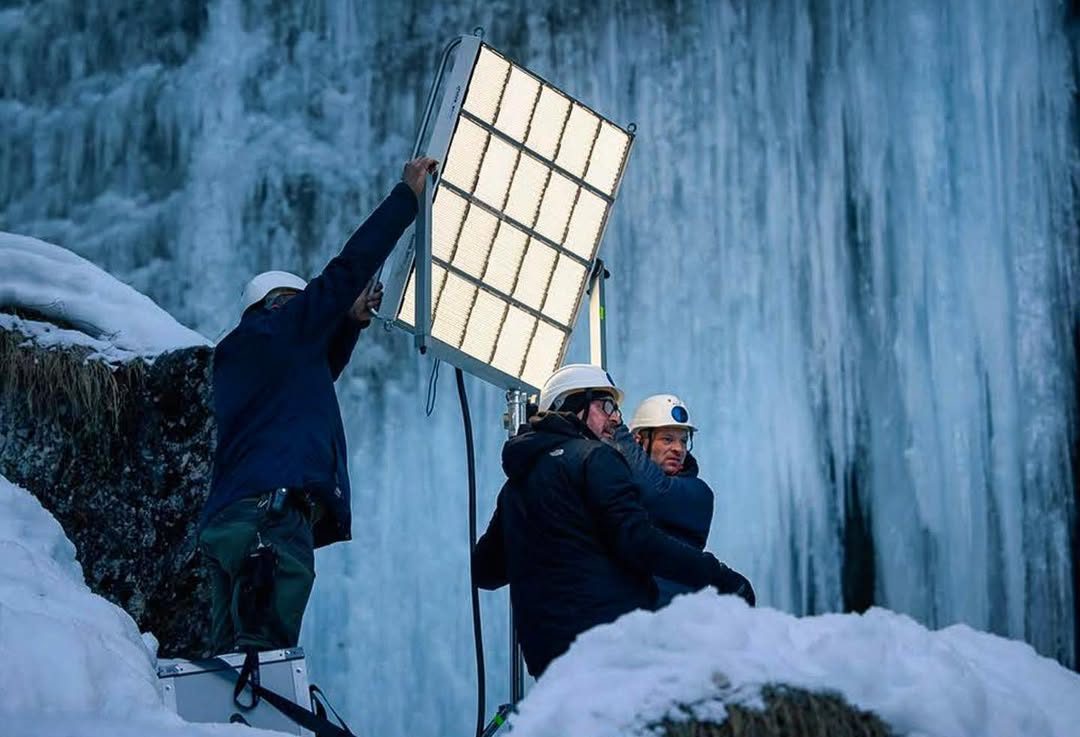 Crew positioning an LED panel in front of a frozen waterfall