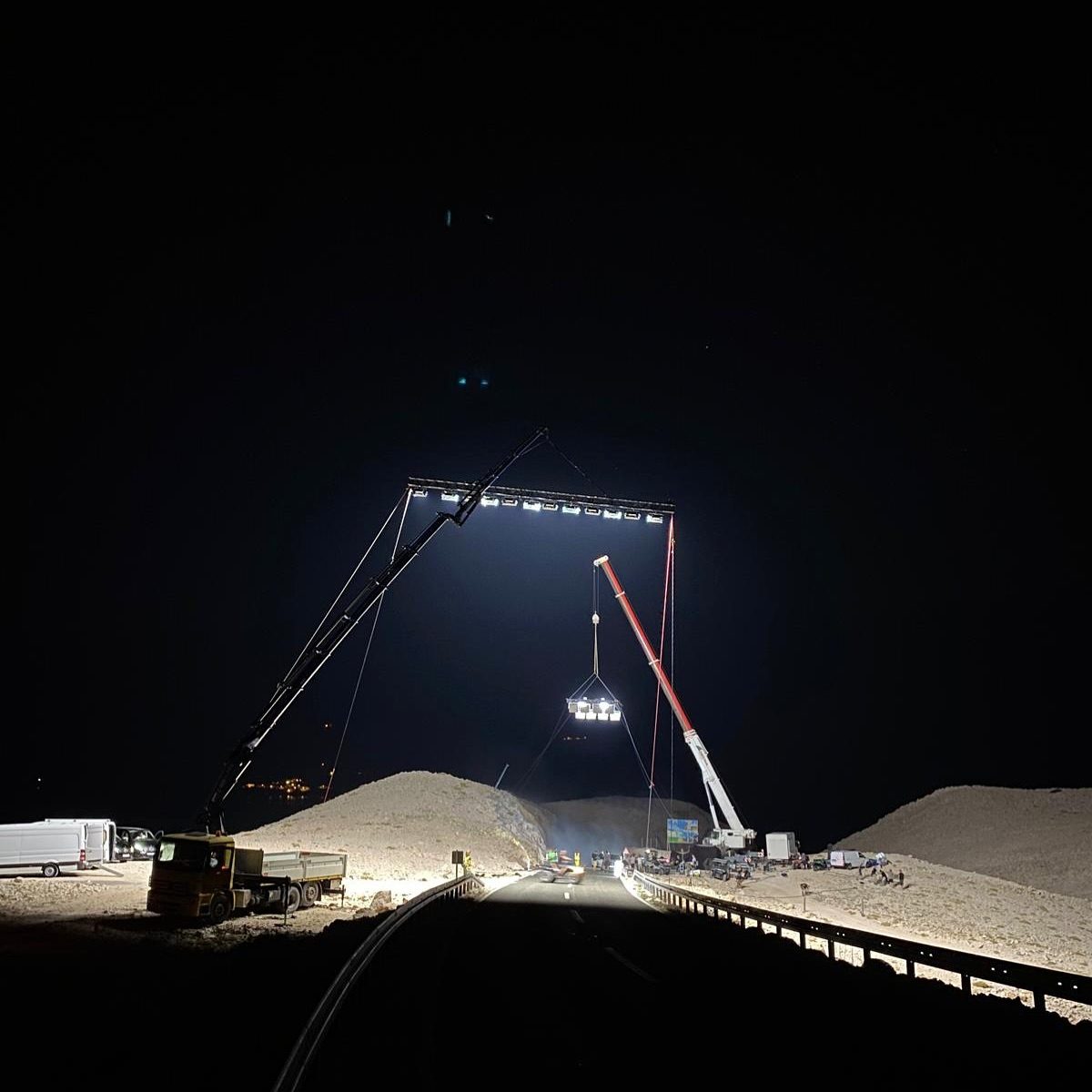 Crane flying a lighting truss over a sand quarry at night