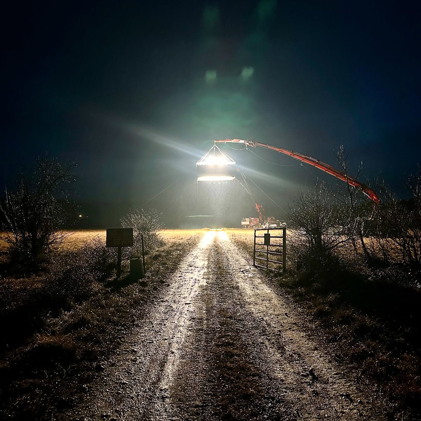 Crane light beaming down a dirt track at night