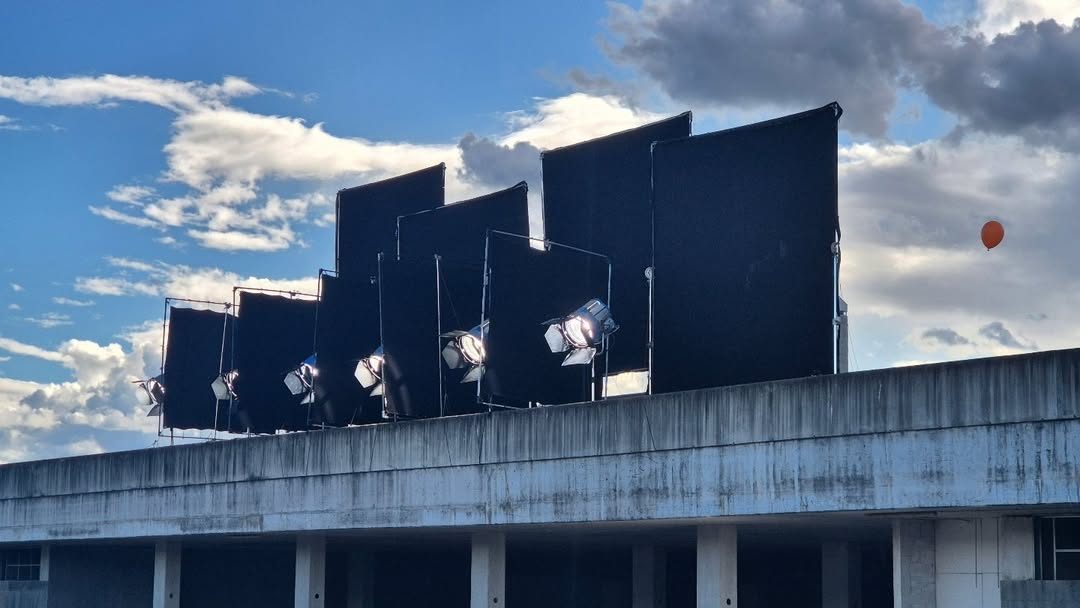 Row of large flags and fixtures rigged on a rooftop against the sky