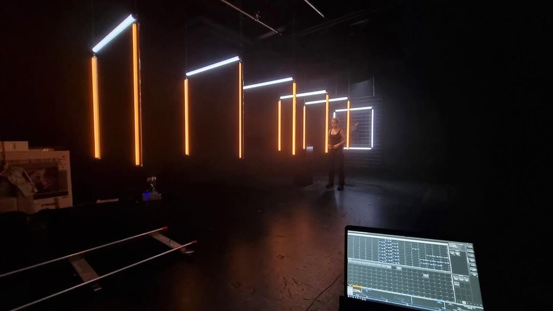 Row of vertical orange LED tubes in a dark studio with a control monitor
