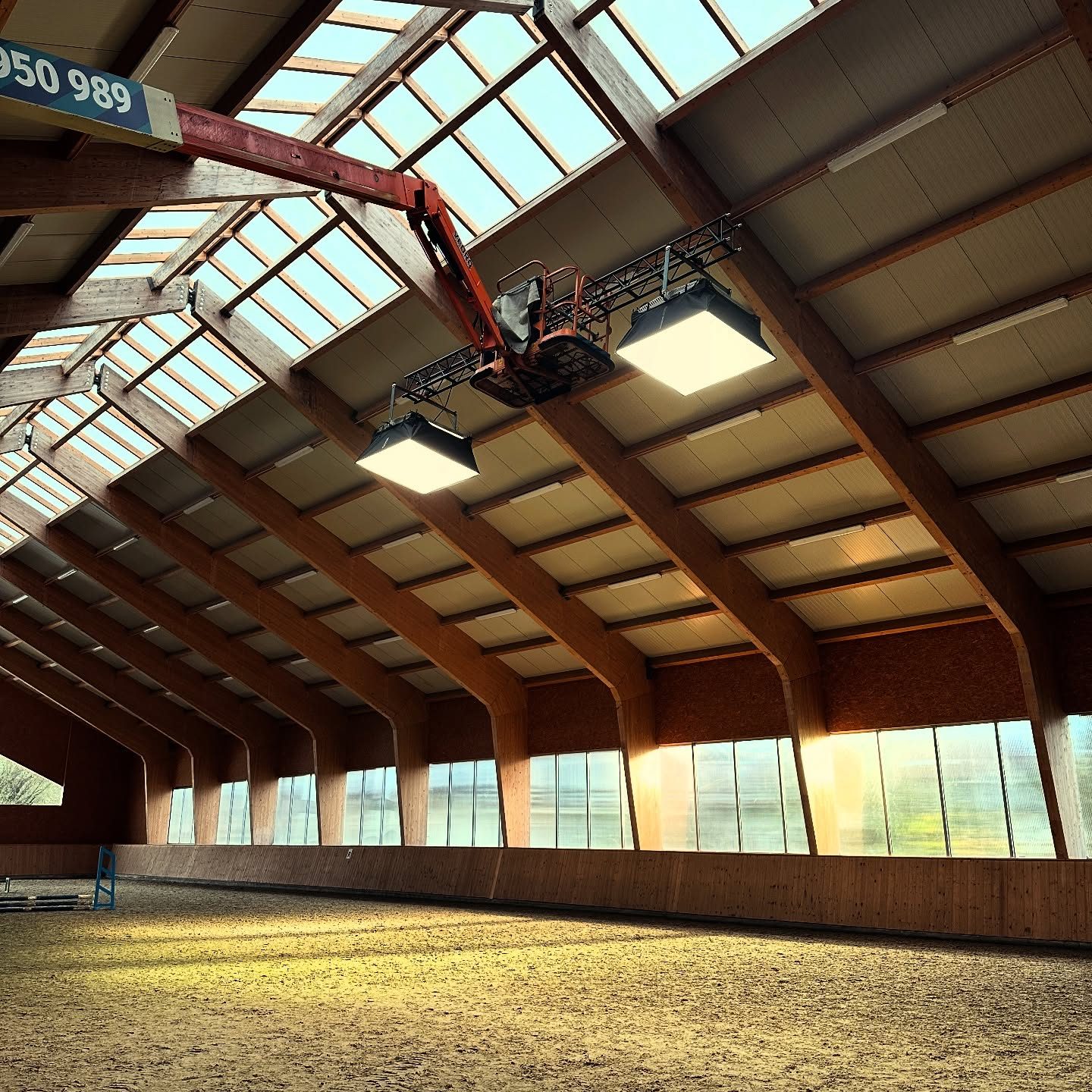 Cherry picker under the timber roof of a daylit indoor arena