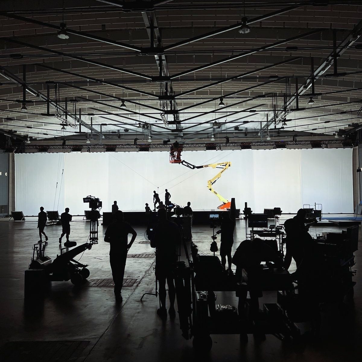 Crew silhouettes and gear in a large white studio